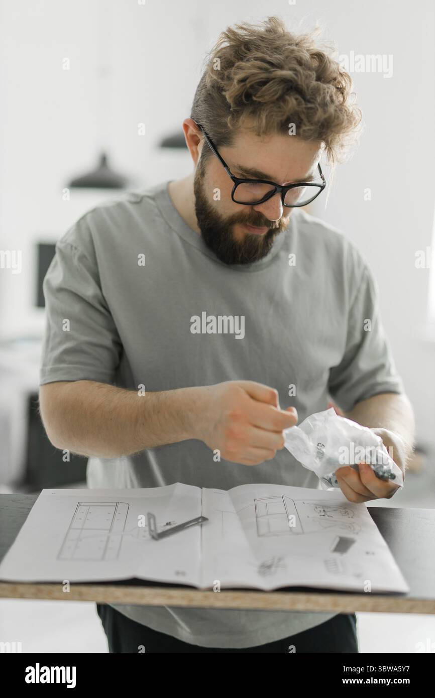 Junger attraktiver Mann baut Möbel - handwerker und Inneneinrichtung Konzept Stockfoto