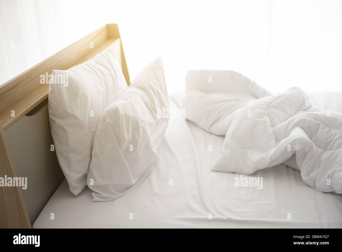 Weiß ungemachten Bett am Morgen mit Sonnenschein mit weißen Vorhang Hintergrund in eleganten Haus. Interior Design und luxuriöse Möbel Konzept. Drinnen lif Stockfoto