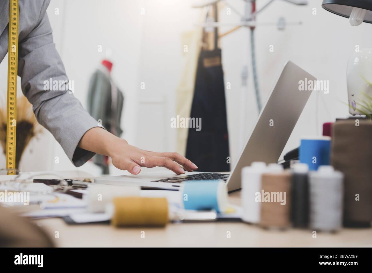 Nahaufnahme der weiblichen Mode Designer arbeiten in der Kleidung Shop Studio und mit laptop computer Kunden zu kontaktieren. Frau erstellen Design neue Colle Stockfoto