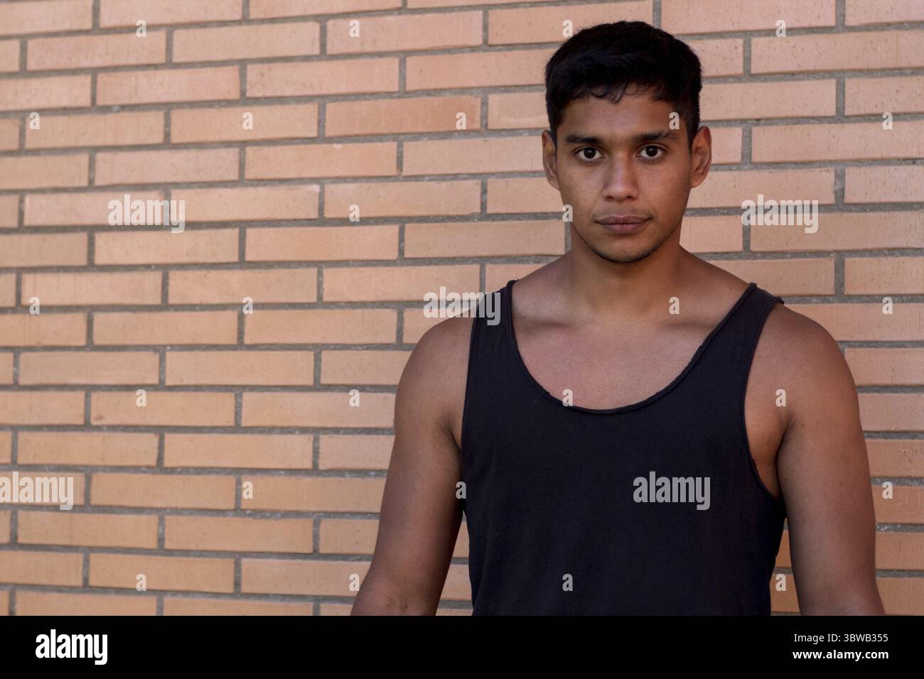 Porträt eines ernsthaften Sportlers lateinamerikanischer Herkunft, der ein schwarzes Tanktop auf der Straße trägt Stockfoto