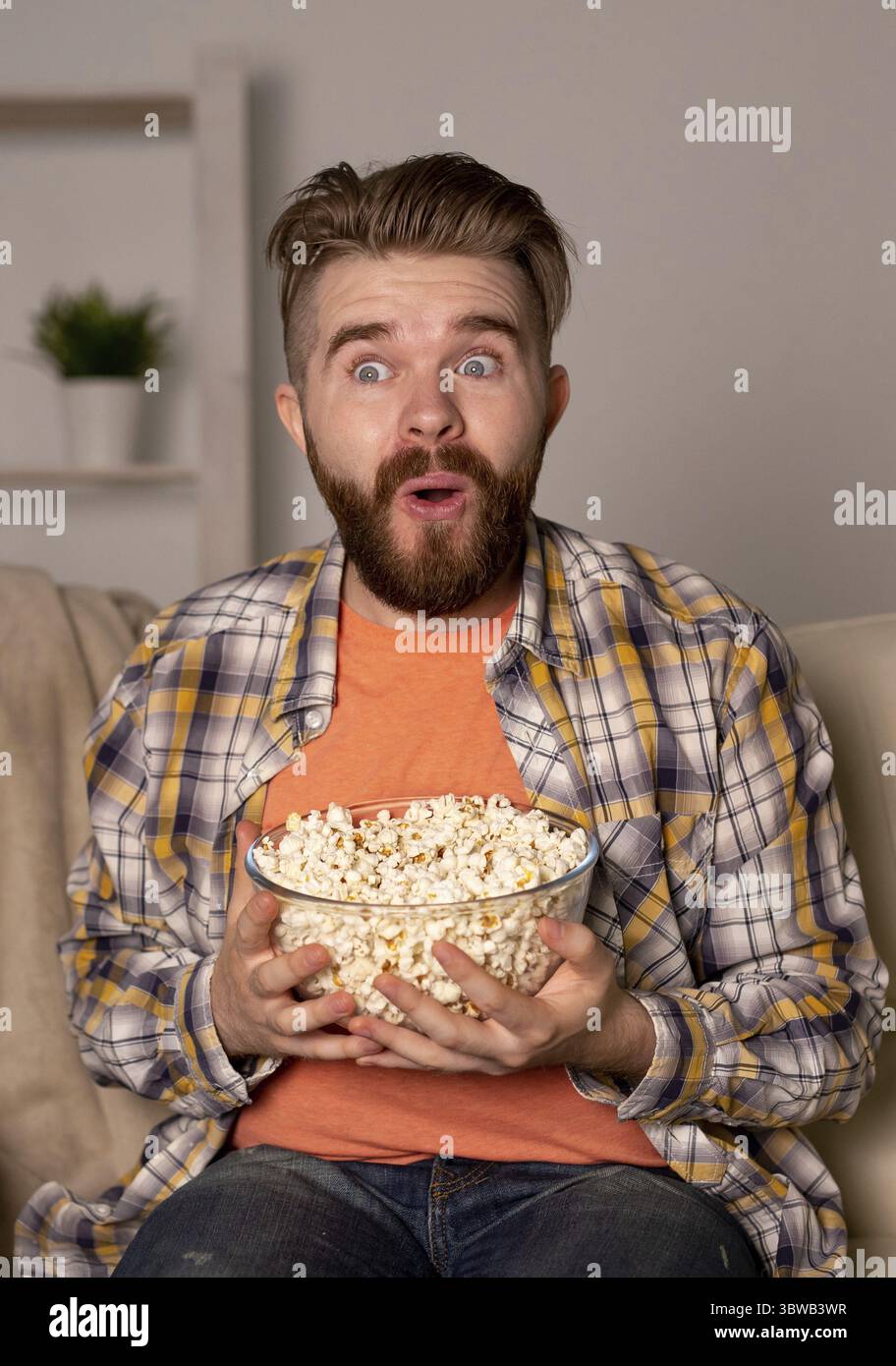 Alleinstehender Mann auf der Couch und sieht in einem Zimmer fern Stockfoto