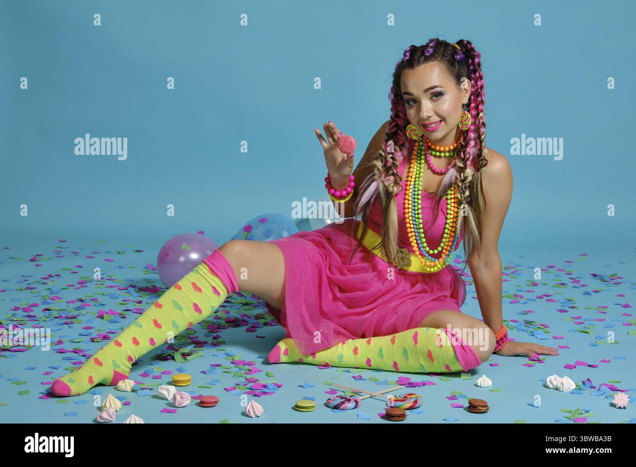 Volle Länge Foto von einer großartigen Dame mit einem bunten Zöpfe Frisur und Make-up. Posiert im Studio mit Luftballons, Eibisch und Konferenzen Stockfoto