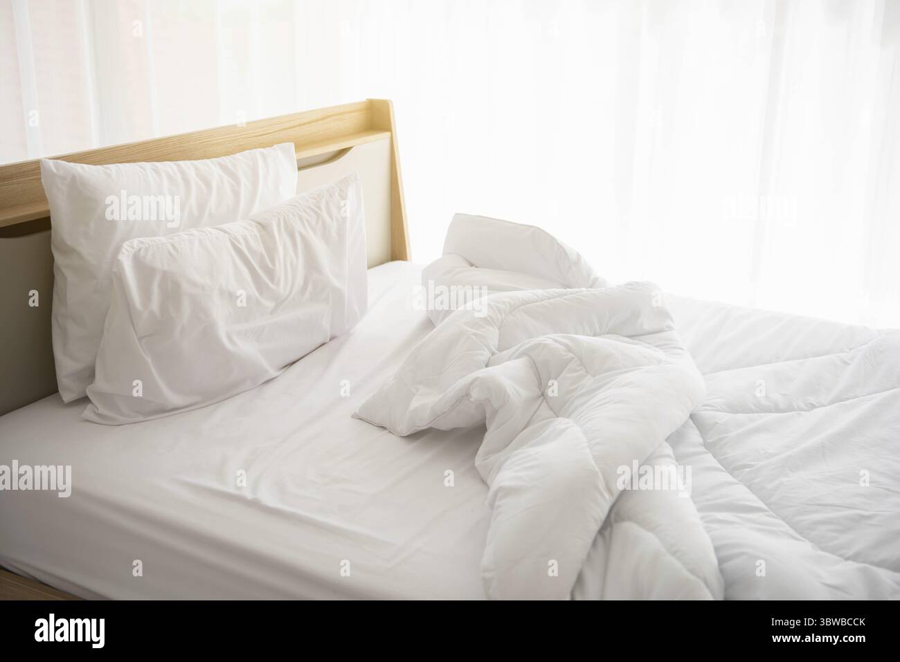 Weiß ungemachten Bett am Morgen mit Sonnenschein mit weißen Vorhang Hintergrund in eleganten Haus. Interior Design und luxuriöse Möbel Konzept. Drinnen lif Stockfoto