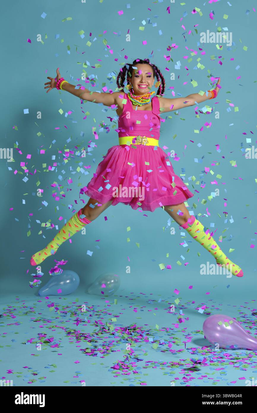 Volle Länge Foto von einer anmutigen Frau mit einem bunten Zöpfe Frisur und Make-up. Posiert im Studio mit Ballons und Konfetti gege Stockfoto