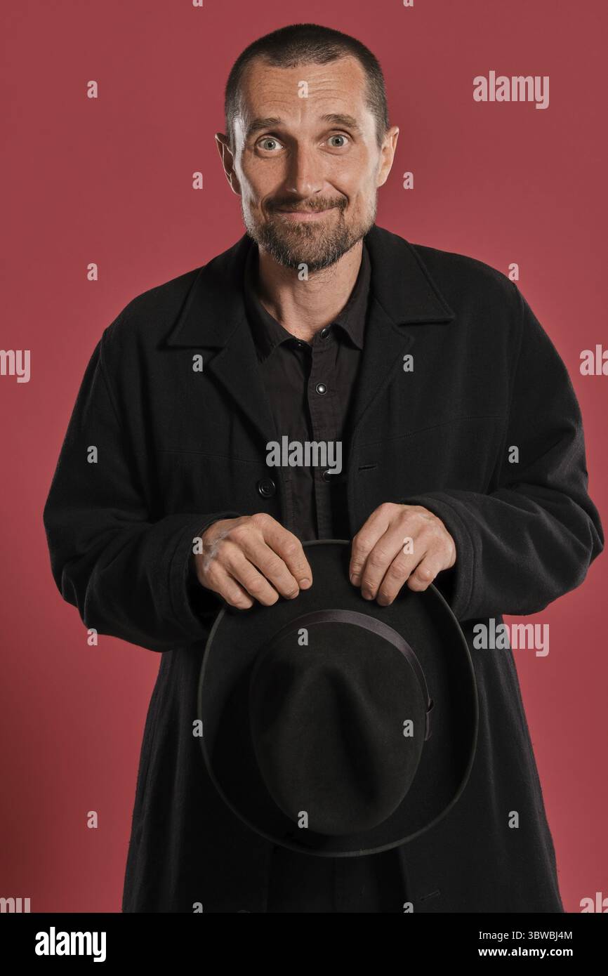 Close-up Studio geschossen von einem erwachsenen Mann mit Bart und Schnurrbart, trägt schwarze Jacke, eine Mütze in seine Arme, und wenn man die Kamera beim Posing Stockfoto