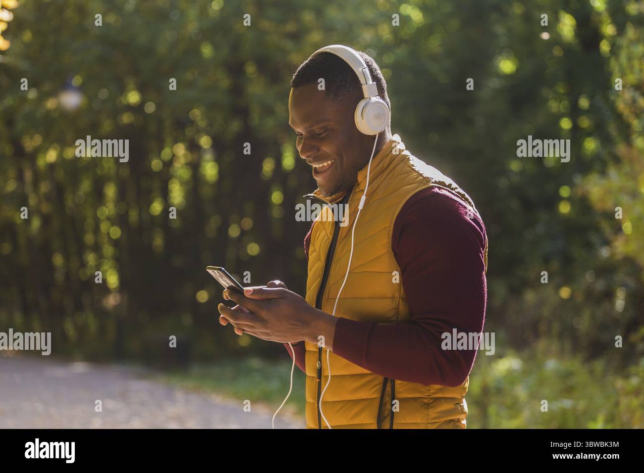 Portraet Afrikanischer amerikanischer Mann hoert Musik im Herbstpark Kopieren Raum und Platz für Text. Gadget, App und Streaming Service Konzept Stockfoto