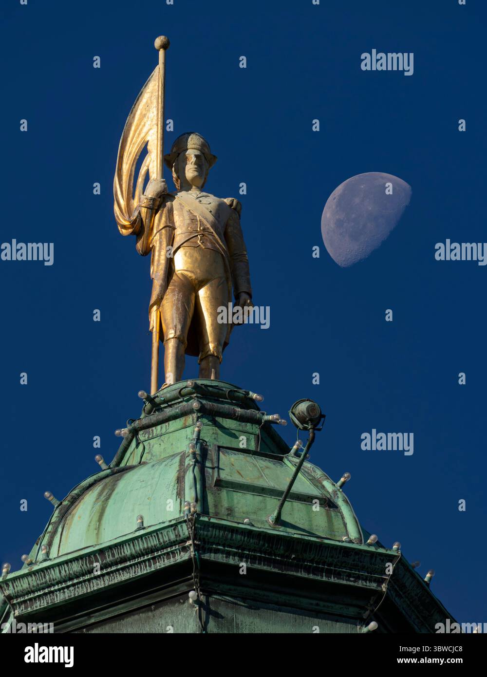 Eine Statue von George Vancouver mit dem Mond am Himmel über den Parlamentsgebäuden von British Columbia in Victoria. Stockfoto