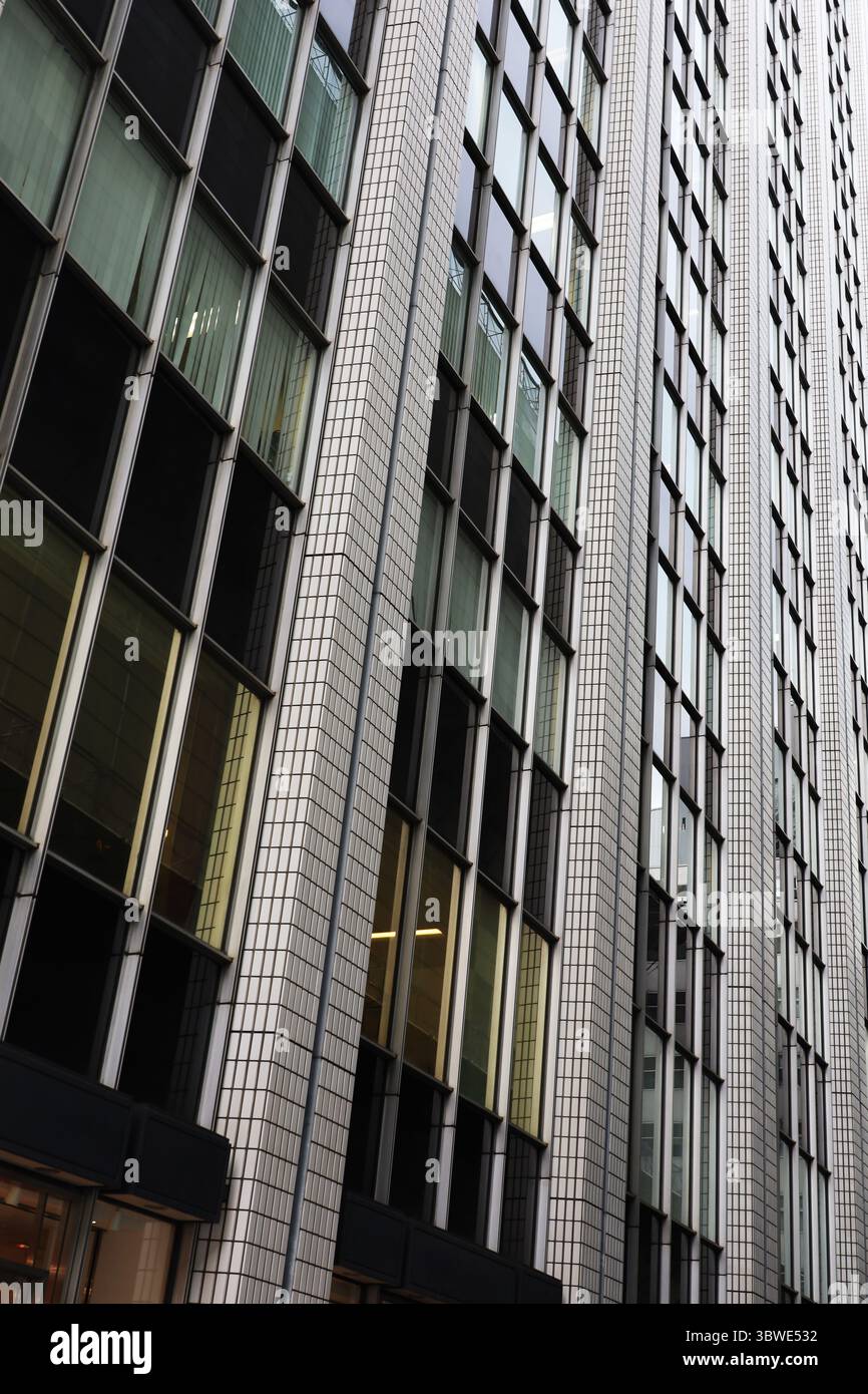 Die Außenwand eines Retro-modernen Hochhauses ist in einem geometrischen Muster mit großen und kleinen geraden Linien gestaltet Stockfoto