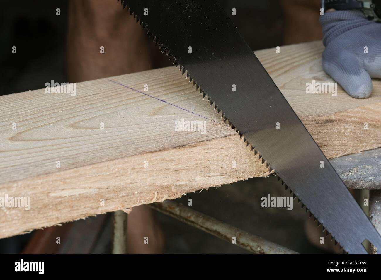 Mann sägt Holz mit Handsäge, Großaufnahme Stockfoto