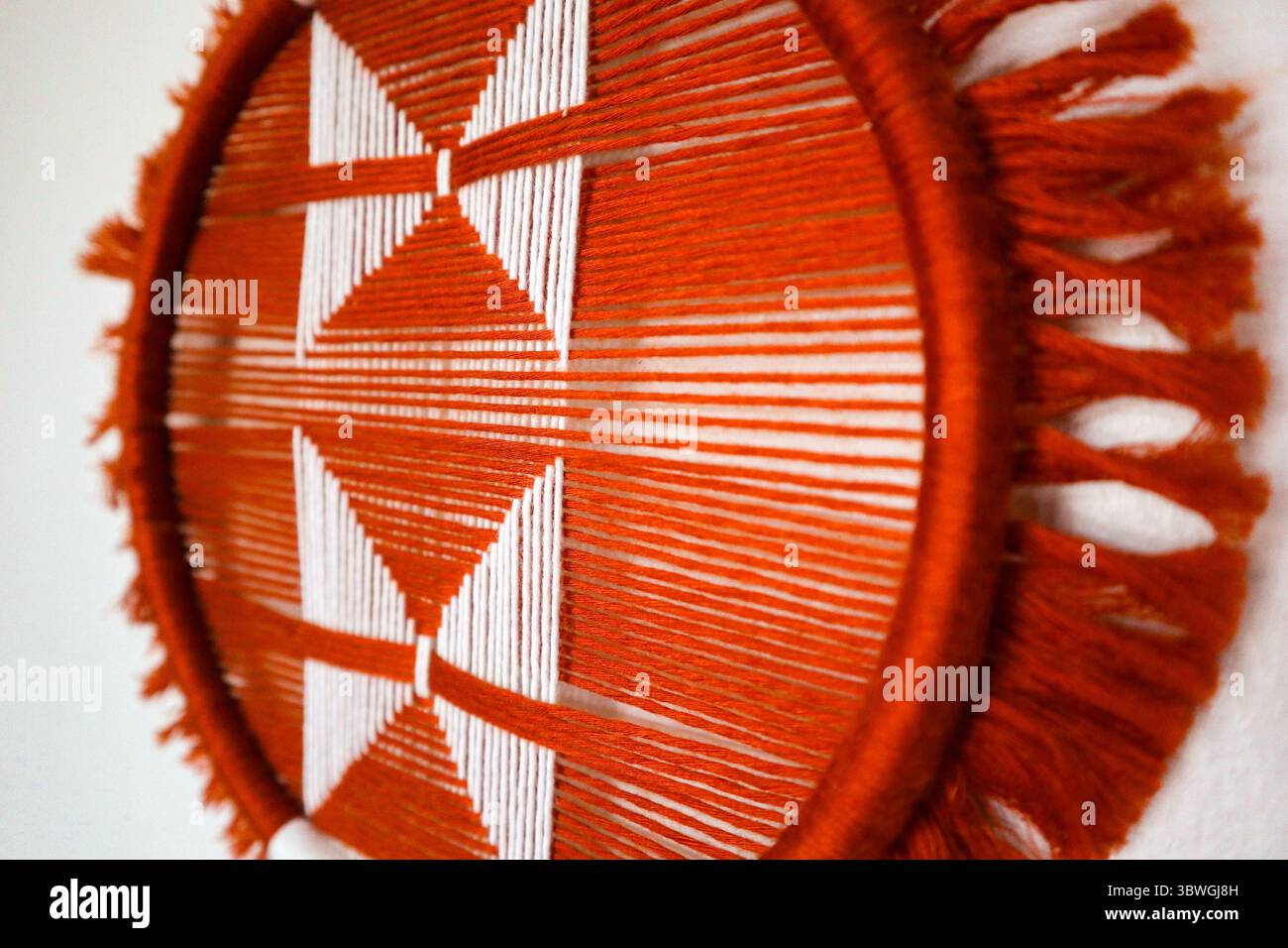 Gewebte Wandbilder mit geometrischem Muster in kräftigen Farbtönen. Eine handgefertigte, gewebte Wandkunst mit auffälligen geometrischen Mustern in lebendigen Erdtönen. Stockfoto