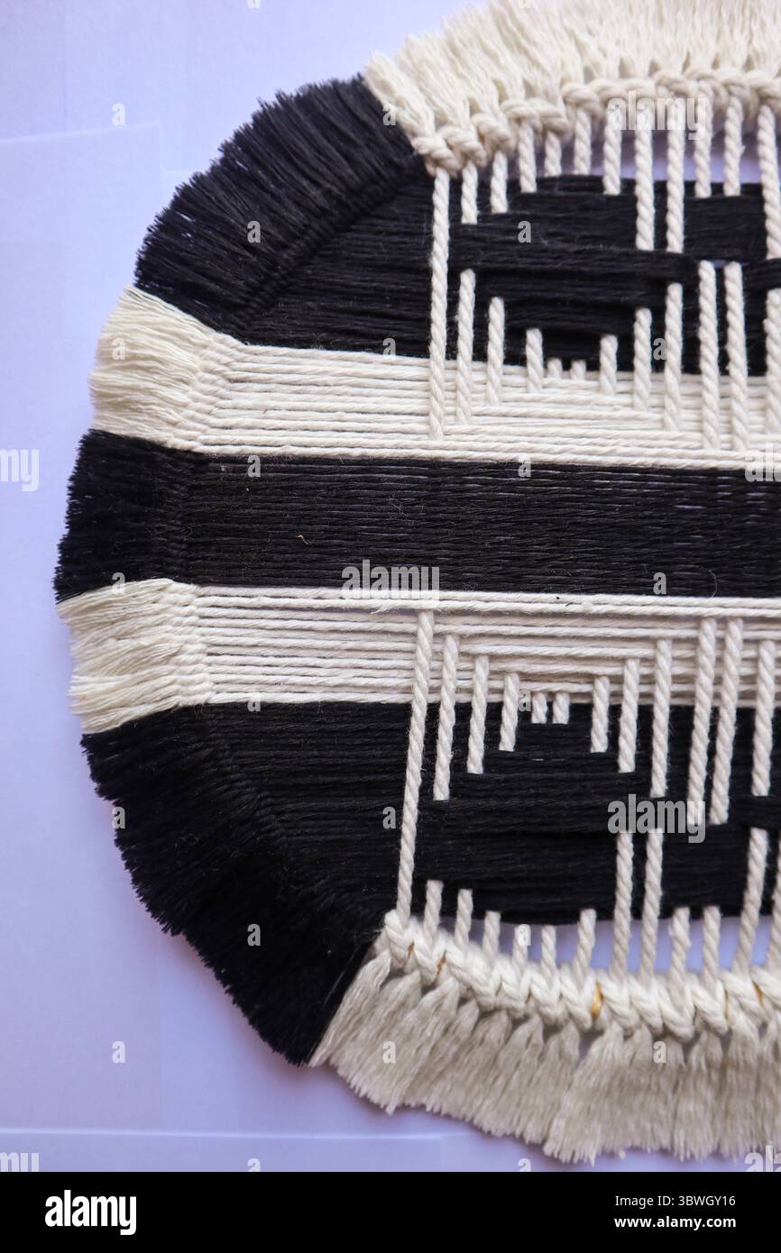 Handgewebte kreisförmige Wandkunst in Schwarz und weiß Ein handgefertigtes, gewebtes Wandkunstwerk in Schwarz-weiß mit modernem geometrischem Design. Stockfoto