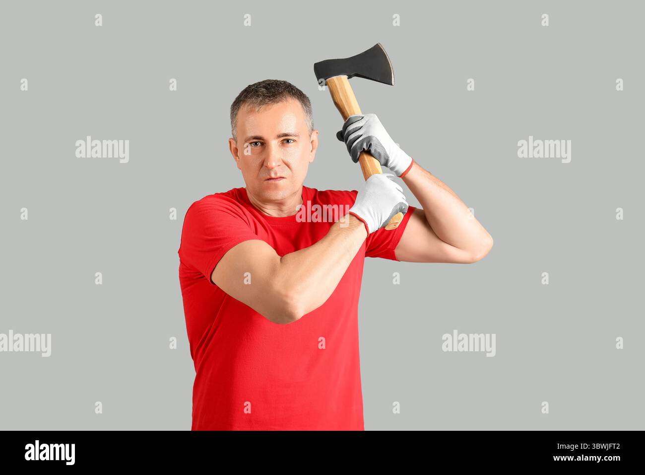 Porträt einer adulten Holzfäller-Schwingaxt auf grauem Hintergrund Stockfoto Porträt einer adulten Holzfäller-Schwingaxt auf grauem Hintergrund Stockfoto