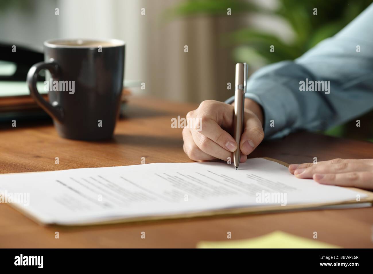 Nahporträt eines Büroarbeiters, der einen Vertrag auf einem Holztisch unterzeichnet Stockfoto