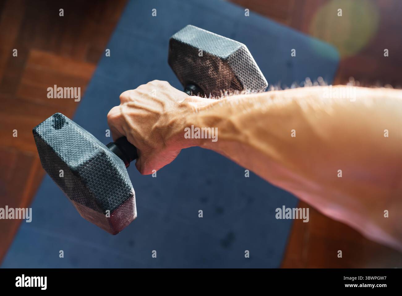 Muskulärer männlicher Arm mit vorstehenden Venen, die schwere Hantel halten Stockfoto