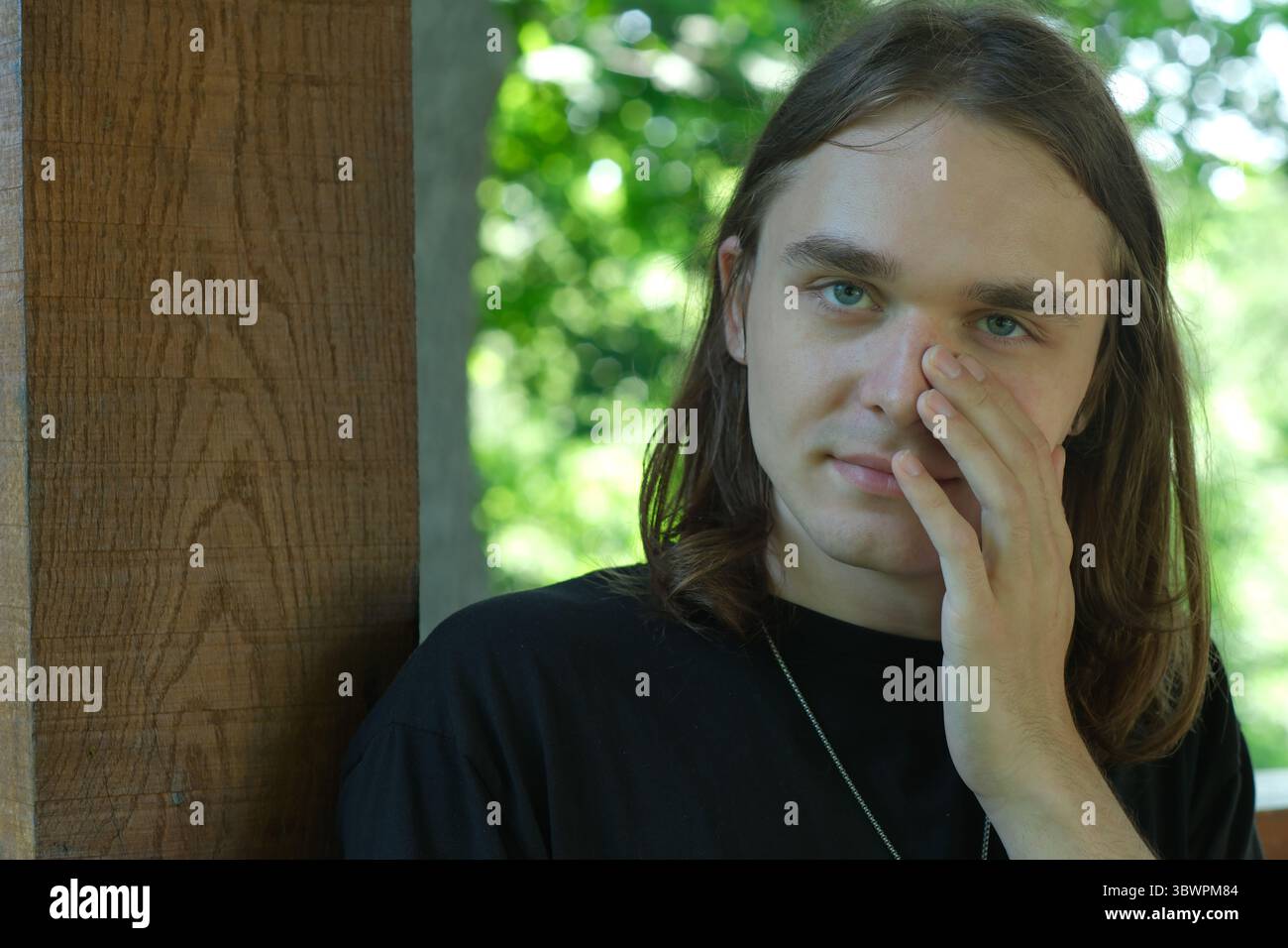 Der junge Mensch reflektiert leise, Hand auf Gesicht, umgeben von der Ruhe der Natur. Stockfoto