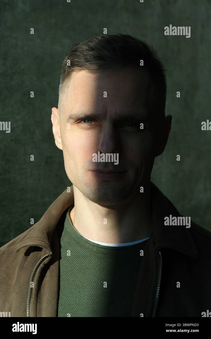 Ein Mann steht leise, halb beleuchtet von sanftem Licht, was eine rätselhafte Atmosphäre schafft. Stockfoto