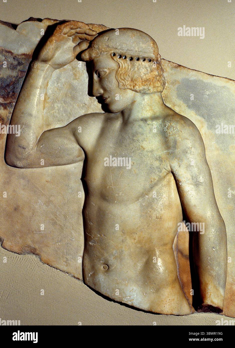 Votivrelief gefunden im Tempel von Athena Sounion 460 v. Chr. Griechenland Griechisches Museum Athen, Griechisches Museum. (Dieses Votivrelief aus Marmor wurde in Sounion gefunden, in der Nähe des Tempels von Athena. Er repräsentiert einen sich selbst krönenden Athleten und wurde wahrscheinlich von einem sieger in lokalen Spielen engagiert. Sein Kranz war aus Metall und wurde an den gebohrten Löchern befestigt, die um den Kopf herum sichtbar sind. Es wurde um 460 v. Chr. hergestellt.) Stockfoto