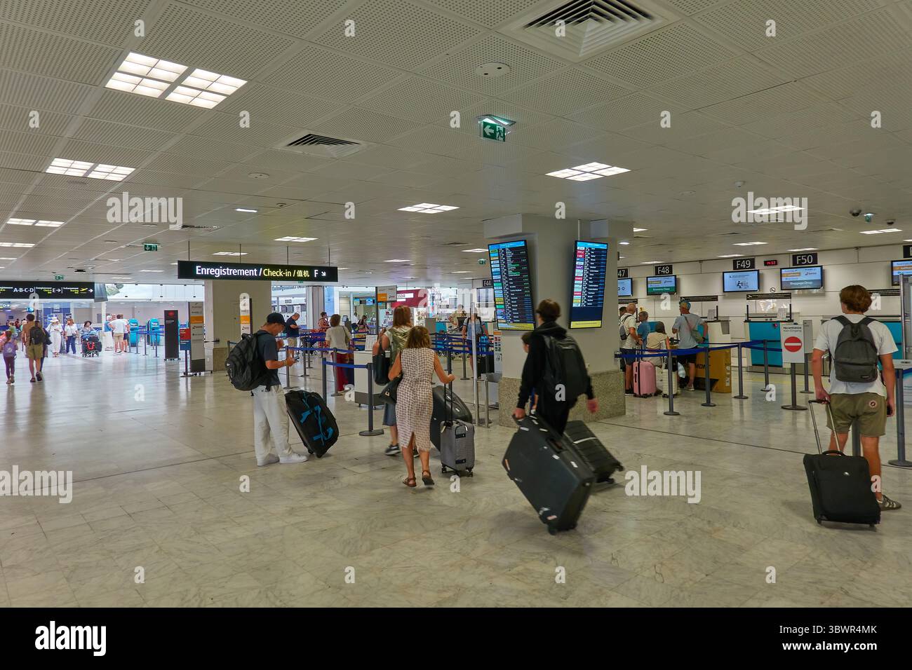 Reisende am Check-in-Bereich des Flughafens, die Abfluginformationen beobachten Stockfoto