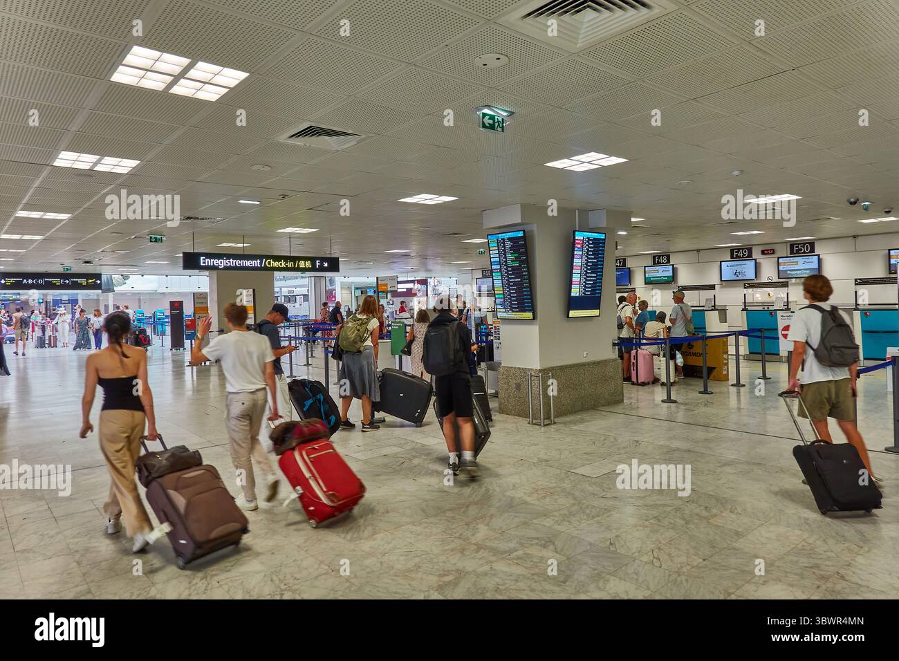 Reisende am Check-in-Bereich des Flughafens, die Abfluginformationen beobachten Stockfoto