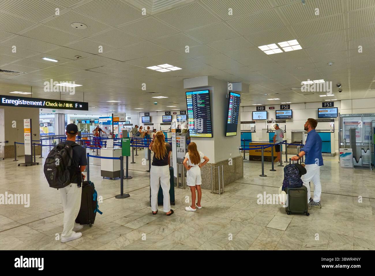 Reisende am Check-in-Bereich des Flughafens, die Abfluginformationen beobachten Stockfoto
