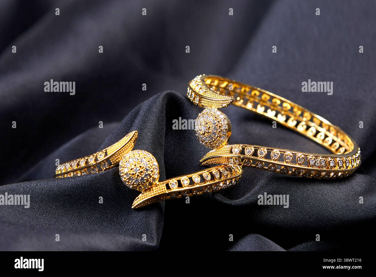Glitzernde goldene Armreifen mit aufwändigen Steindetails, glänzenden Kugeln und eleganten Kurven. Diese Ba ist perfekt für festliche oder Braut-Looks Stockfoto