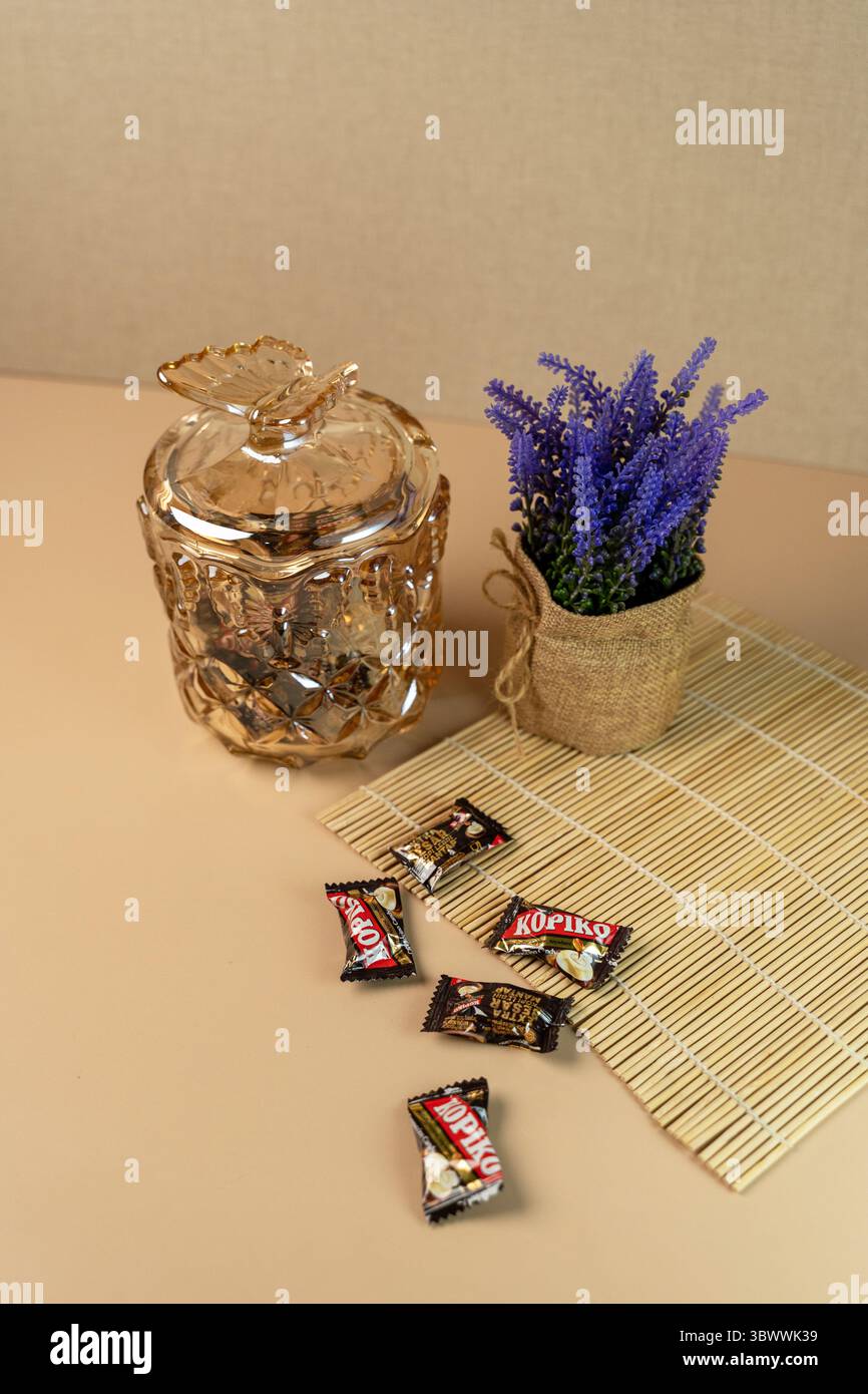 Jakarta, Indonesien, 17. Juli 2025: Dekoratives Braunglas mit Schmetterlingsdeckel, Kaffeespezialitäten und Lavendel auf einer Bambusmatte. Stockfoto