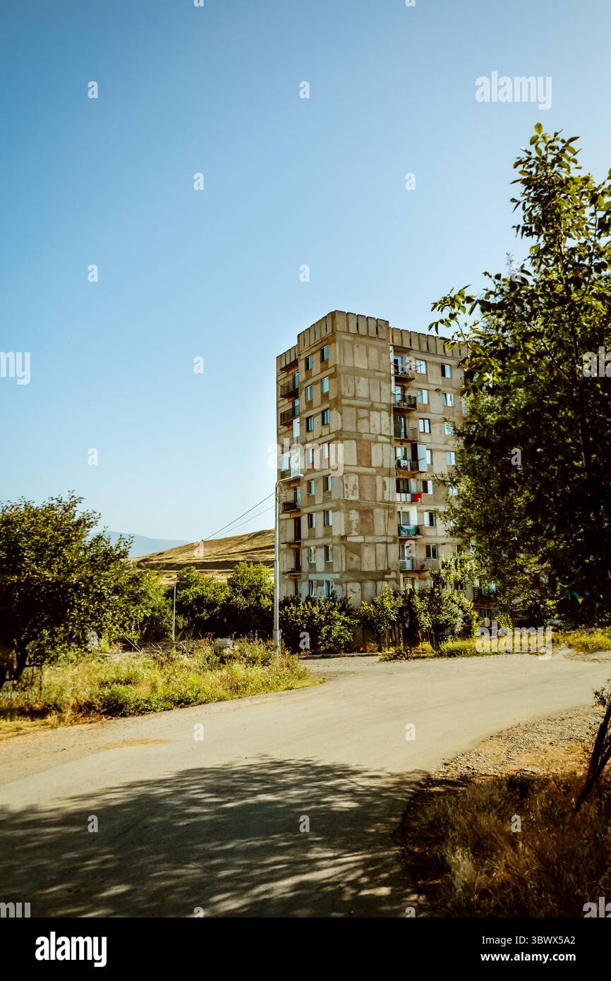 Abgelegene Hochhäuser unterstreichen ein sonnengebleichtes Grasland außerhalb von Tiflis, Georgien, unter einem weiten, wolkenlosen Mittagshimmel mit viel Kopierraum Stockfoto