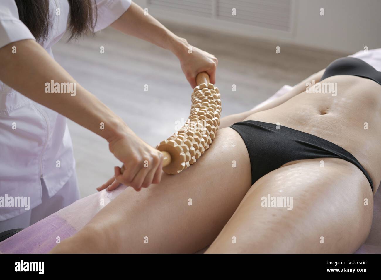 Stimulation des Lymphsystems mit holztherapeutischer Behandlung. Massieren Sie mit einer Holzrolle, um Flüssigkeiten und Cellulite zu beseitigen. Verbessern Sie die Durchblutung in der le Stockfoto