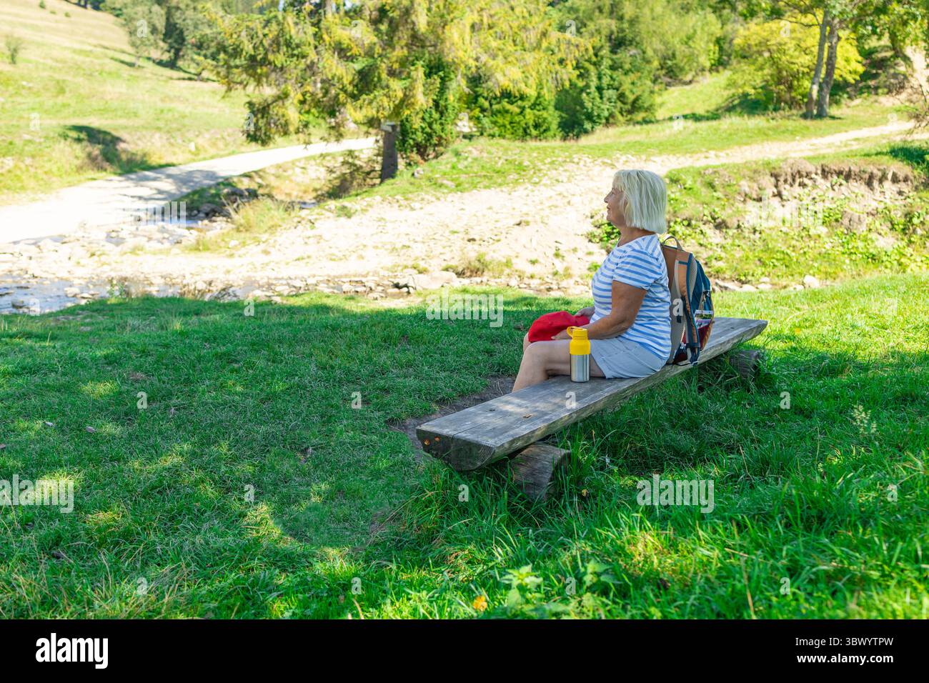Seniorin ruht auf einer Bank während der Wanderung in der Natur Stockfoto