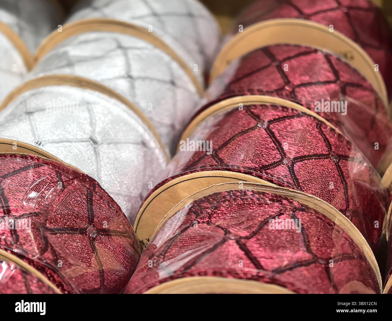 Leuchtend rote und glänzende silberne Bänder sind übersichtlich in Reihen angeordnet und präsentieren ihre gewebten Muster und ihren metallischen Glanz. Perfekt für einen Hauch Stockfoto