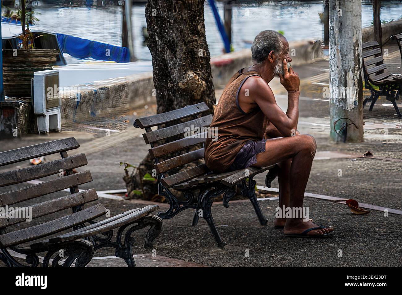 Salvador, Bahia, Brasilien – 10. März 2025. Ein Ferntelefoto-Bild eines Mannes, der auf einer Parkbank denkt. Stockfoto