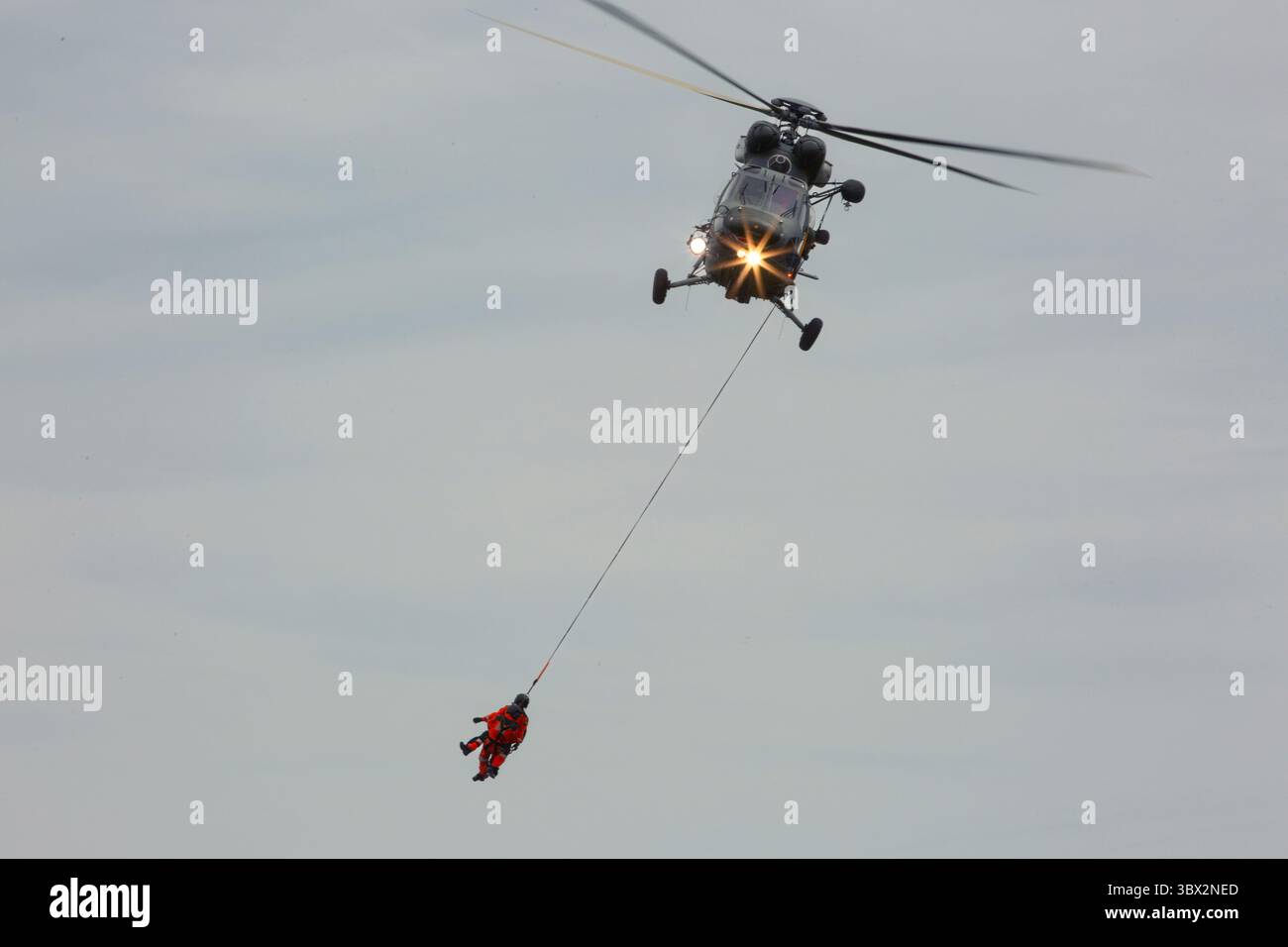 Ein kleiner Hubschrauber fliegt bei der Flugschau hinter dem dunklen Himmel Stockfoto Ein kleiner Hubschrauber fliegt bei der Flugschau hinter dem dunklen Himmel Stockfoto
