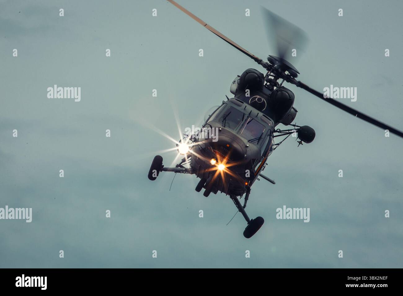 Ein kleiner Hubschrauber fliegt bei der Flugschau hinter dem dunklen Himmel Stockfoto Ein kleiner Hubschrauber fliegt bei der Flugschau hinter dem dunklen Himmel Stockfoto