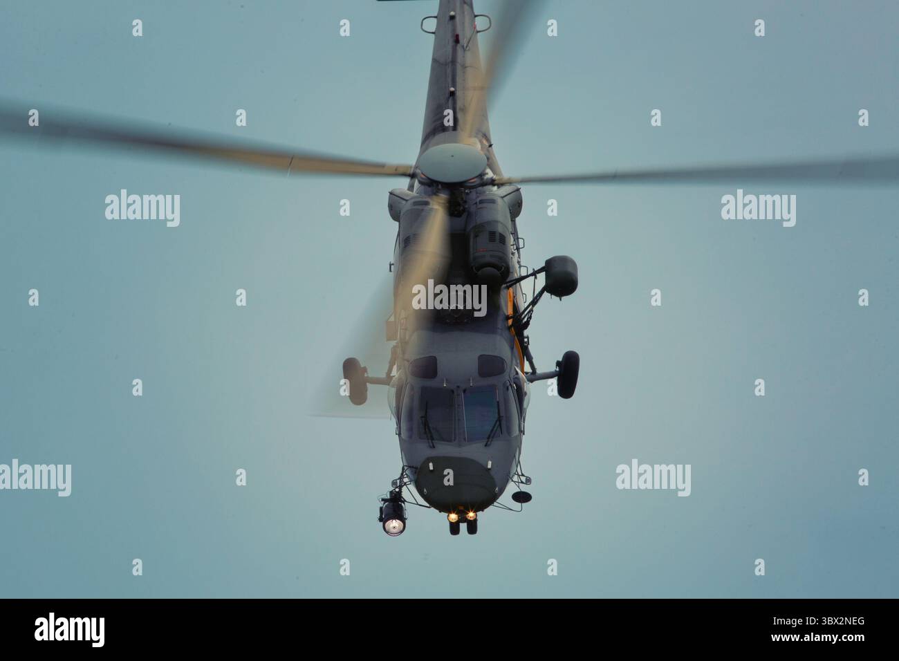 Ein kleiner Hubschrauber fliegt bei der Flugschau hinter dem dunklen Himmel Stockfoto Ein kleiner Hubschrauber fliegt bei der Flugschau hinter dem dunklen Himmel Stockfoto