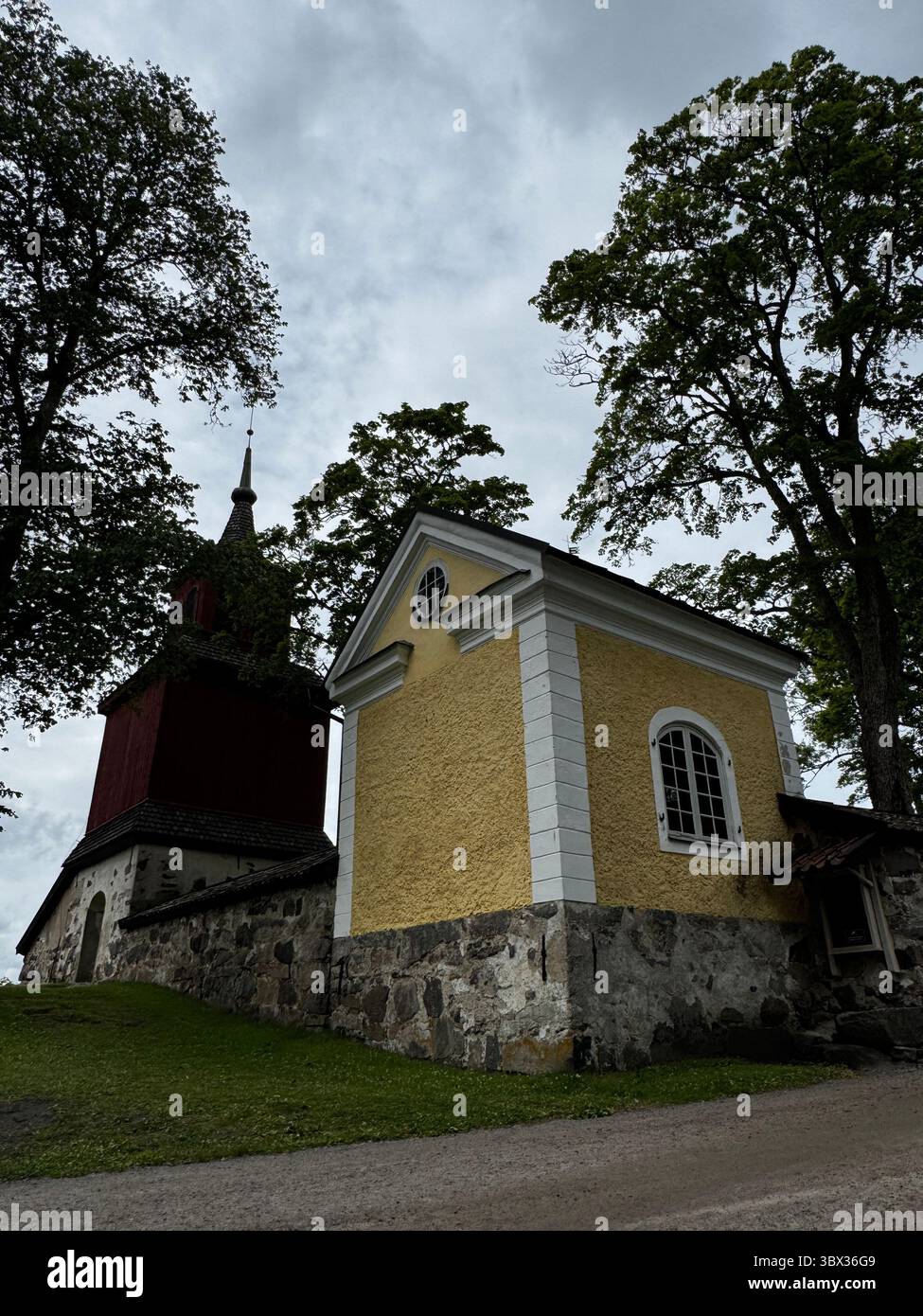 Seitenansicht der Fagervik-Kirche und des Glockenturms in Inkoo, Finnland, die Architektur aus dem 18. Jahrhundert repräsentiert das finnische religiöse Erbe. - Smartphone-aufgenommenes Stockfoto