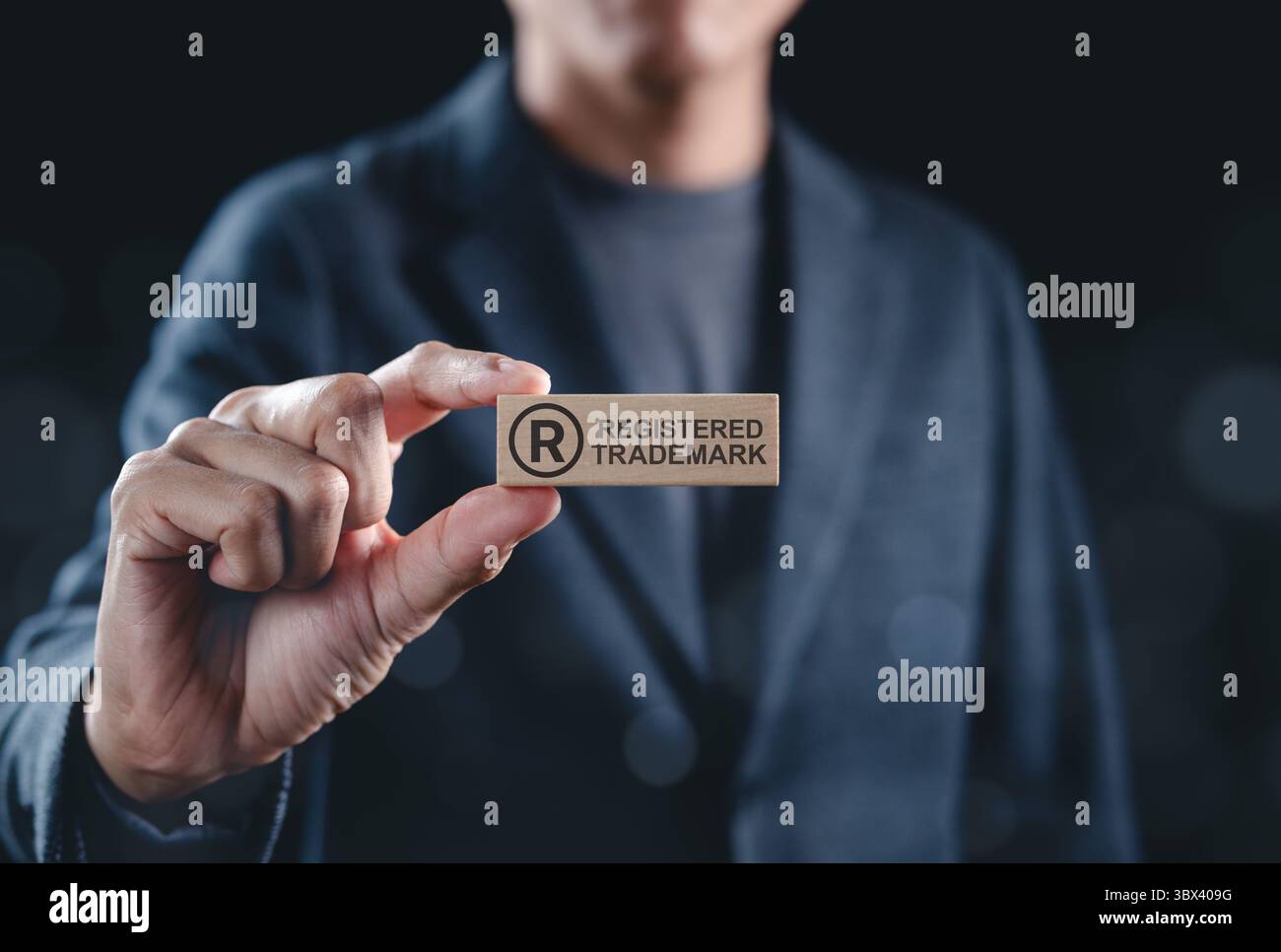 Eingetragenes Markenzeichen und Konzept des geistigen Eigentums. Der Mann hält ein eingetragenes Markensymbol aus Holzblock Stockfoto