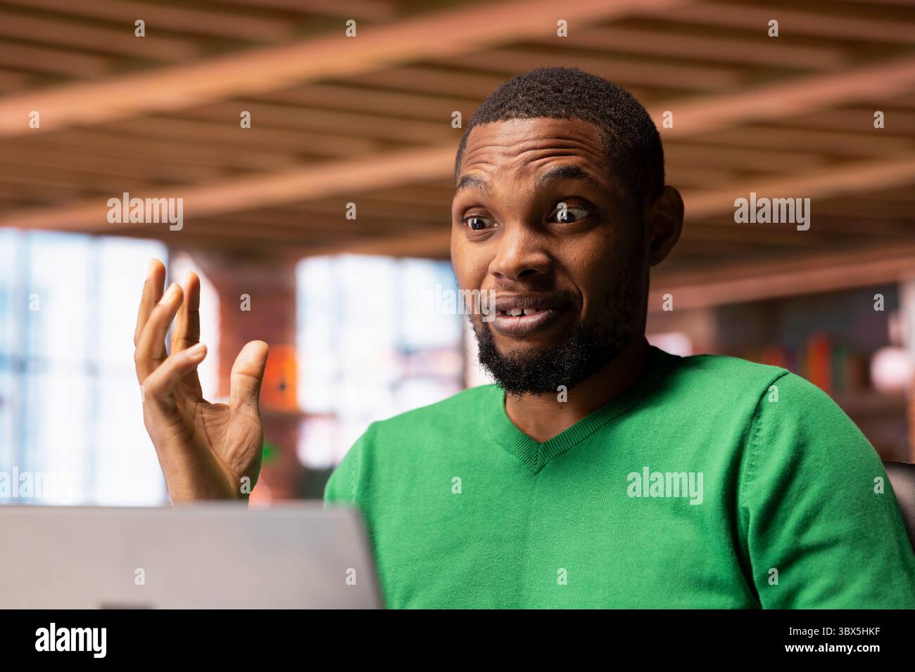 Begeisterter Mann, der ansprechende TV-Serien auf einem Laptop ansieht, fasziniert von fesselnden Action. Nahaufnahme eines afroamerikaners in der Wohnung, überrascht von einer schockierenden Drehung des Films Stockfoto