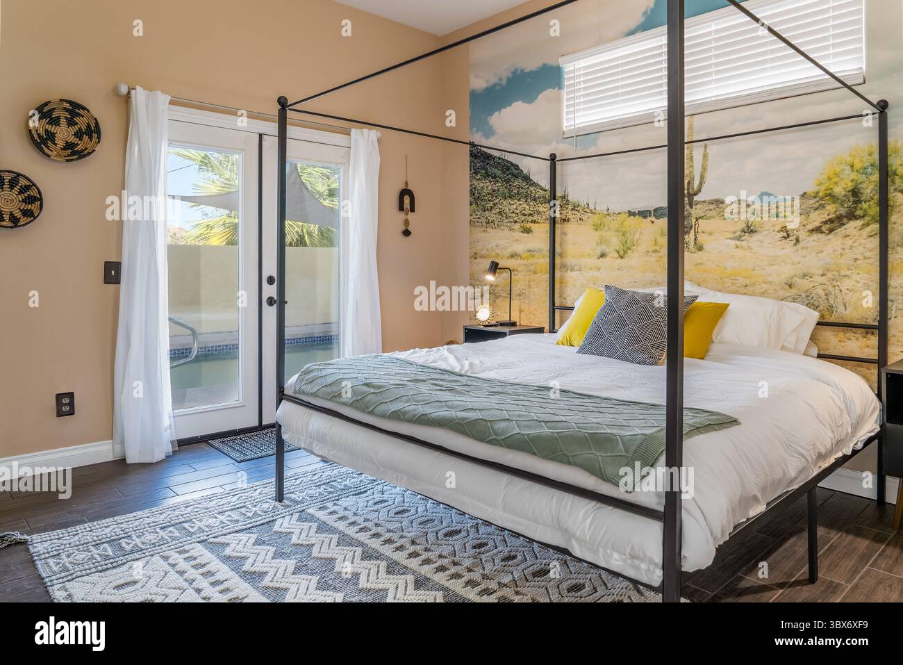 Modernes Schlafzimmer mit Wüstenmotiv, Himmelbett, Kissen, Teppich und Glastüren Stockfoto