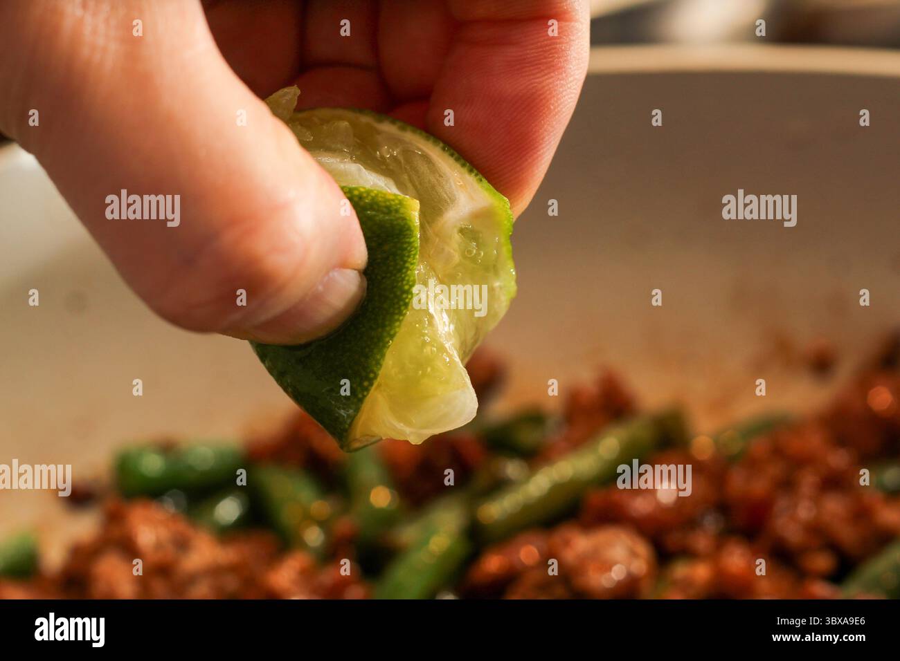 Limettensaft über kochende Speisen drücken Stockfoto