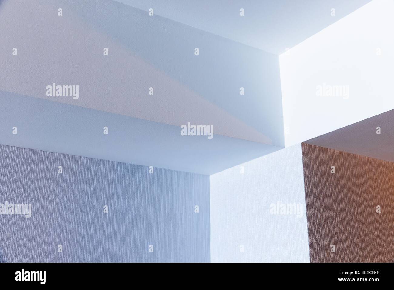 Geometrische Architekturformen schaffen ein abstraktes Muster an einer strukturierten Decke mit sanfter Beleuchtung. Das ima verfügt über ein minimalistisches und modernes Design Stockfoto