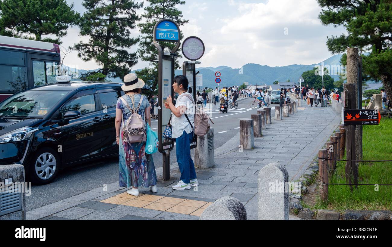 Die Leute warten an einer Bushaltestelle in Arashiyama, Kyoto, Japan, während Taxis und Busse vorbeifahren. Kyoto, Japan. 06.29.2025. Stockfoto