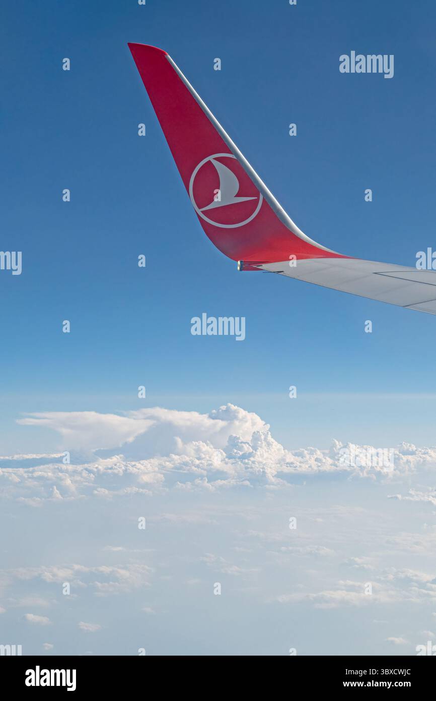Dieser Fensterblick umrahmt den Himmel mit Eleganz und fängt den Flügel und das Logo der Turkish Airlines ein, das über ruhigen Wolken aufragt Stockfoto
