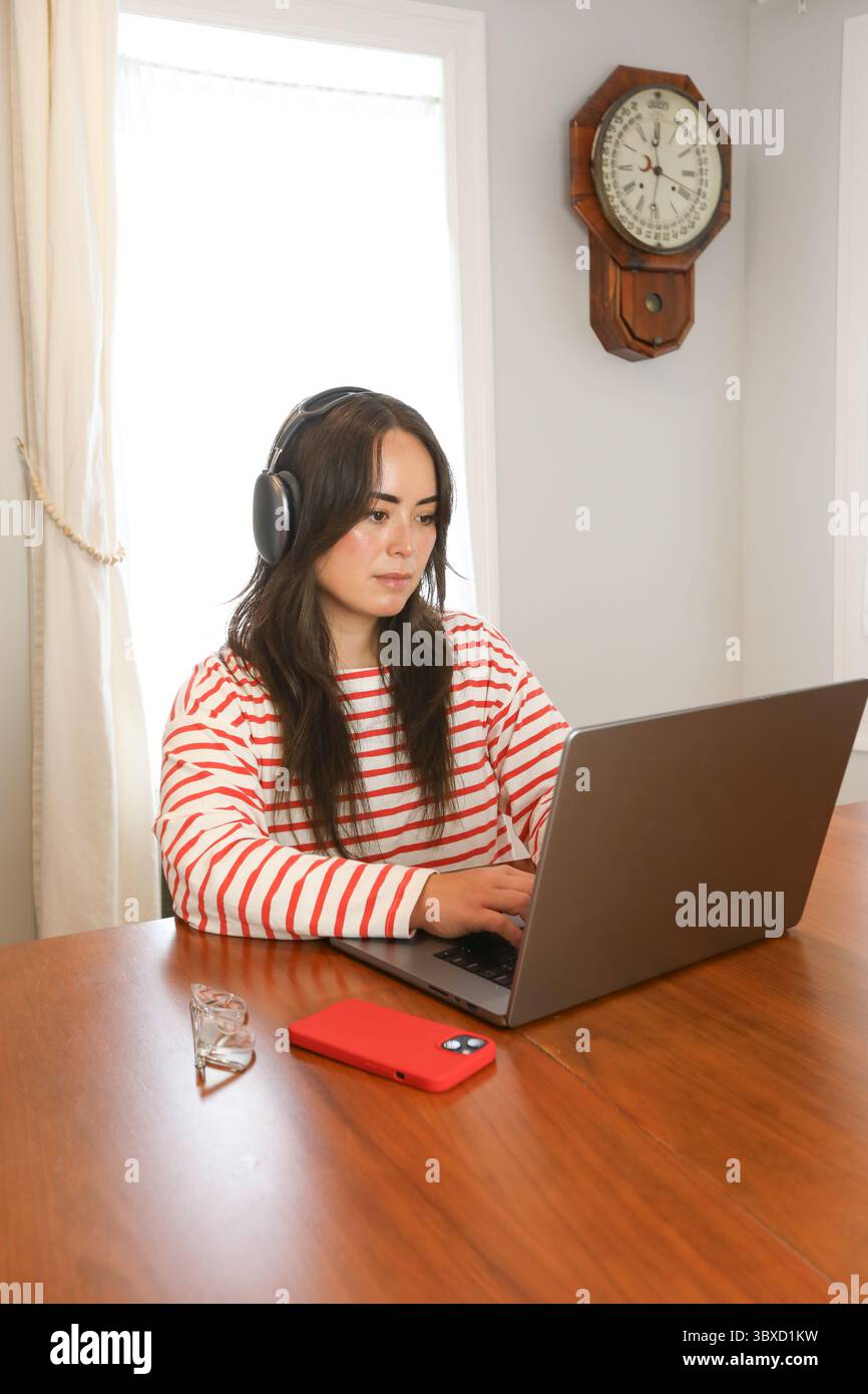 Frau, die von zu Hause aus kabellose Kopfhörer trägt Stockfoto