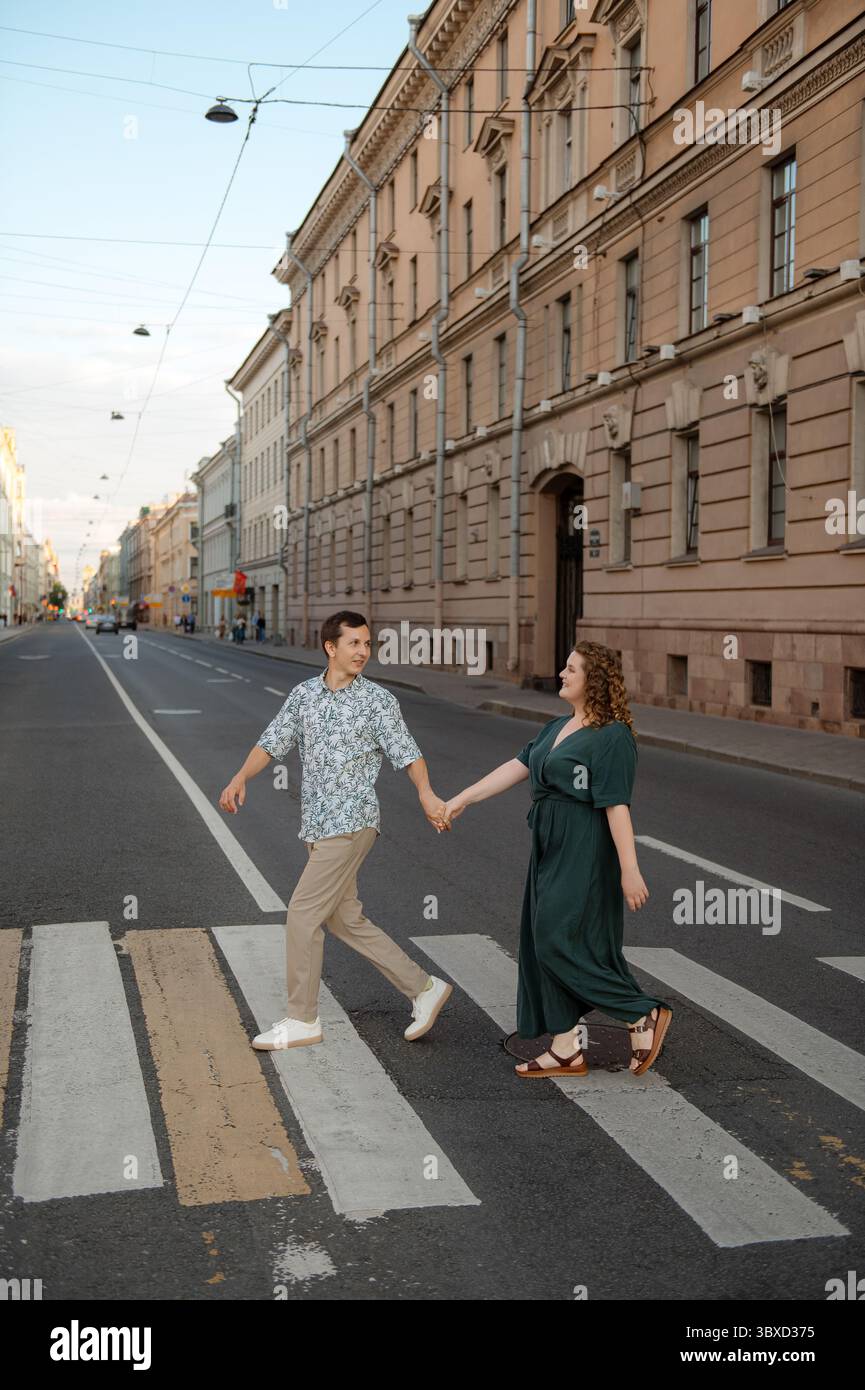 Ein Paar überquert eine ruhige Straße bei Sonnenuntergang in einer Stadt Stockfoto