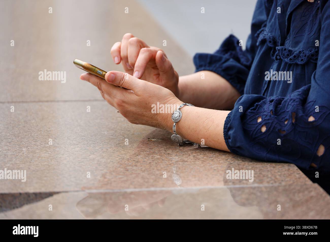 Smartphone in weiblichen Händen auf der Straße. Reife Frau mit Handy in der Sommerstadt Stockfoto
