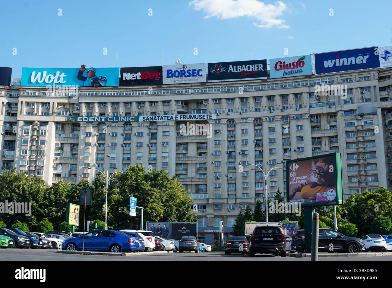 Bukarest, Rumänien – 13. Juli 2025: Wohnblocks, Autos auf dem Parkplatz und Werbetafeln von Marken auf dem Siegesplatz Stockfoto