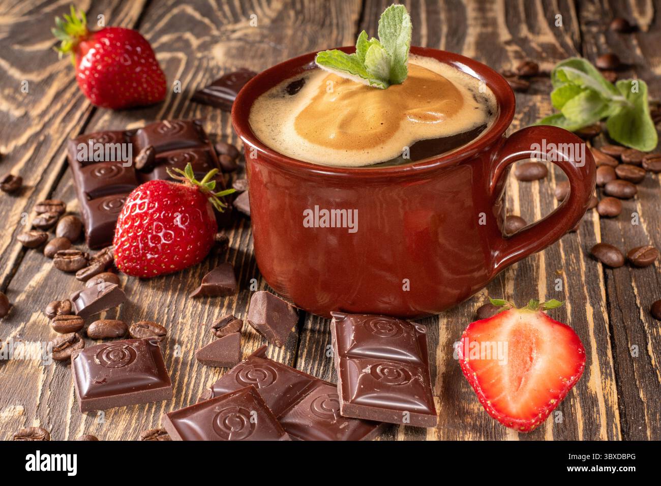 Erleben Sie die wunderbare Kombination aus einer reichhaltigen Tasse Kaffee, begleitet von üppigen Erdbeeren, dekadenten Stücken Schokolade und aromatischen Kaffeebohne Stockfoto