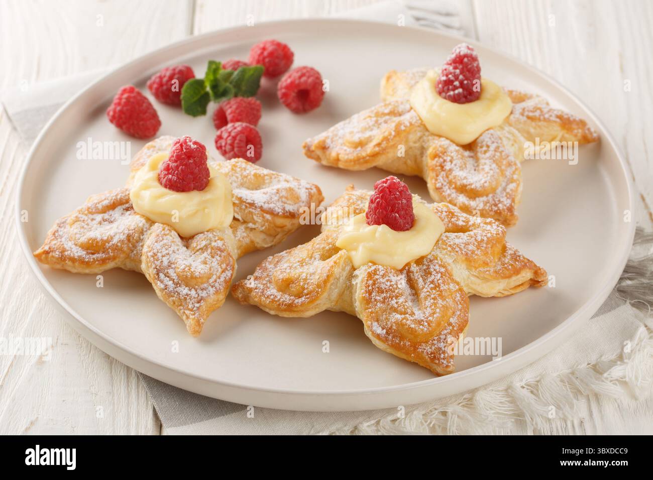 Vanillepuffer-Gebäck gefüllt mit zarter Vanillepudding-Creme und frischen Himbeeren in Nahaufnahme auf einem Teller auf dem Tisch. Horizontal Stockfoto