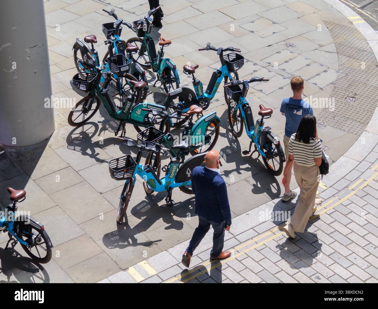 Fußgänger bewegen sich in der City of London, Großbritannien, um zahlreiche Mietfahrräder herum, die auf dem Bürgersteig herumlaufen, was die wachsende Besorgnis über die Behinderung des öffentlichen Raums durch Fahrräder ohne Dock hervorhebt. Stockfoto