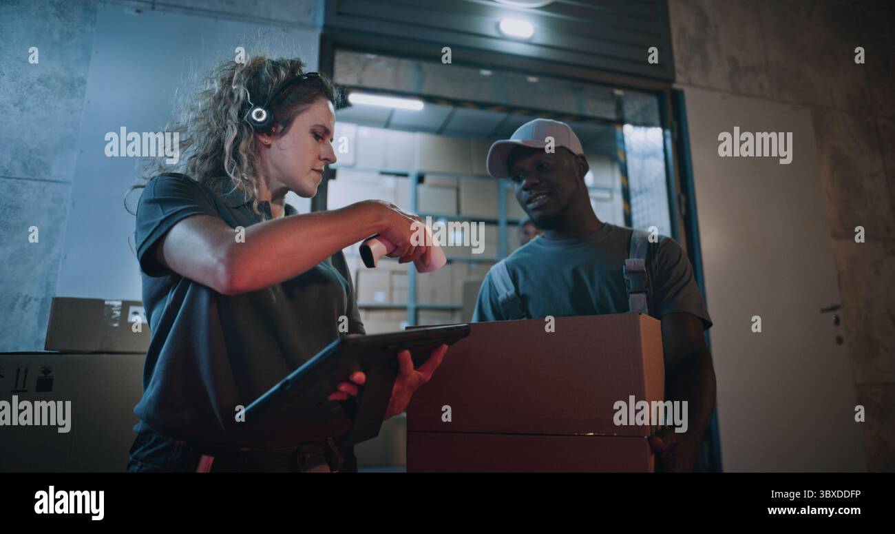 Weibliche Inventory Manager scannt Kartonschachteln mit Strichcode-Scanner mit Tablet-Computer. Multiethnische Arbeiter, die Pakete mit Online-Bestellungen transportieren, Waren aus dem Logistikeinzelhandelslager nachts. Stockfoto